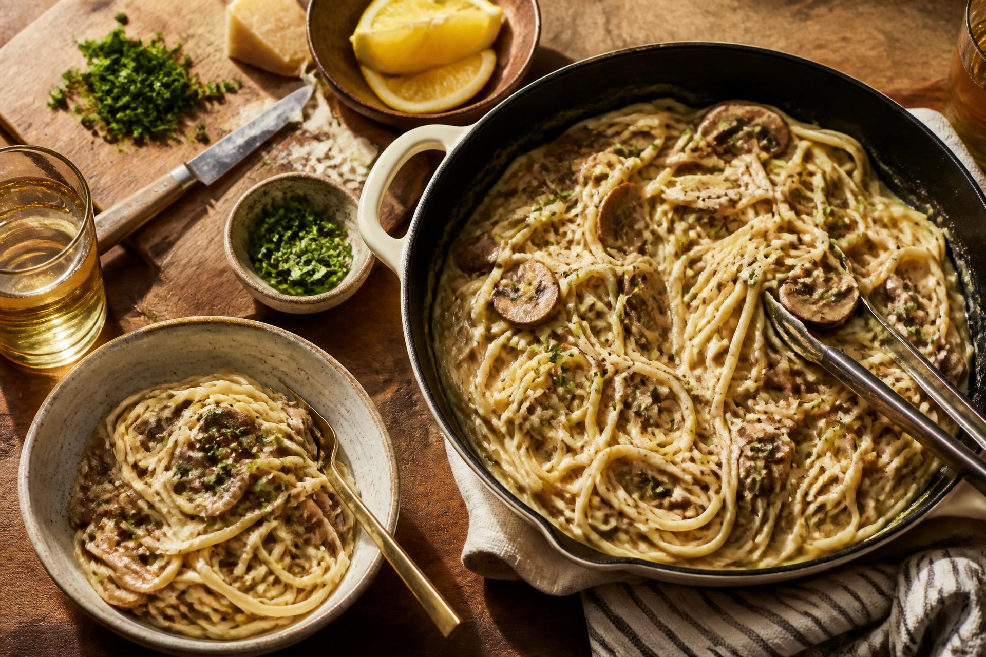 Creamy garlic mushroom linguine in a skillet with herbs and lemon on a wooden weeknight dinner table